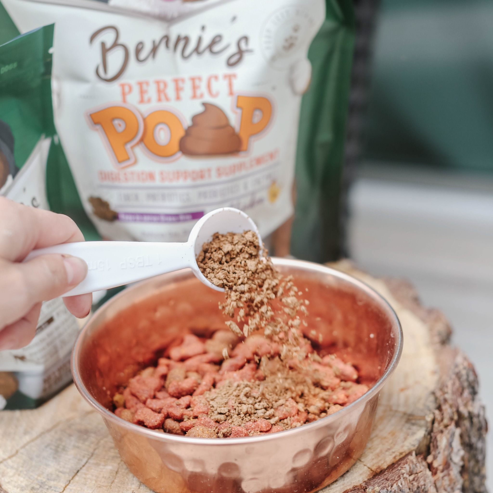 Photo: A person scoops Bernie's Perfect Poop into their dog's food bowl.